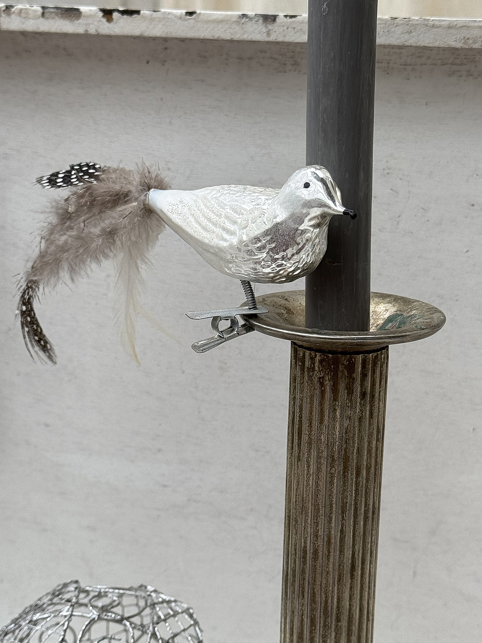 Schöner dekorativer Vogel aus Holz mit Federn, befestigt an einem Kerzenhalter