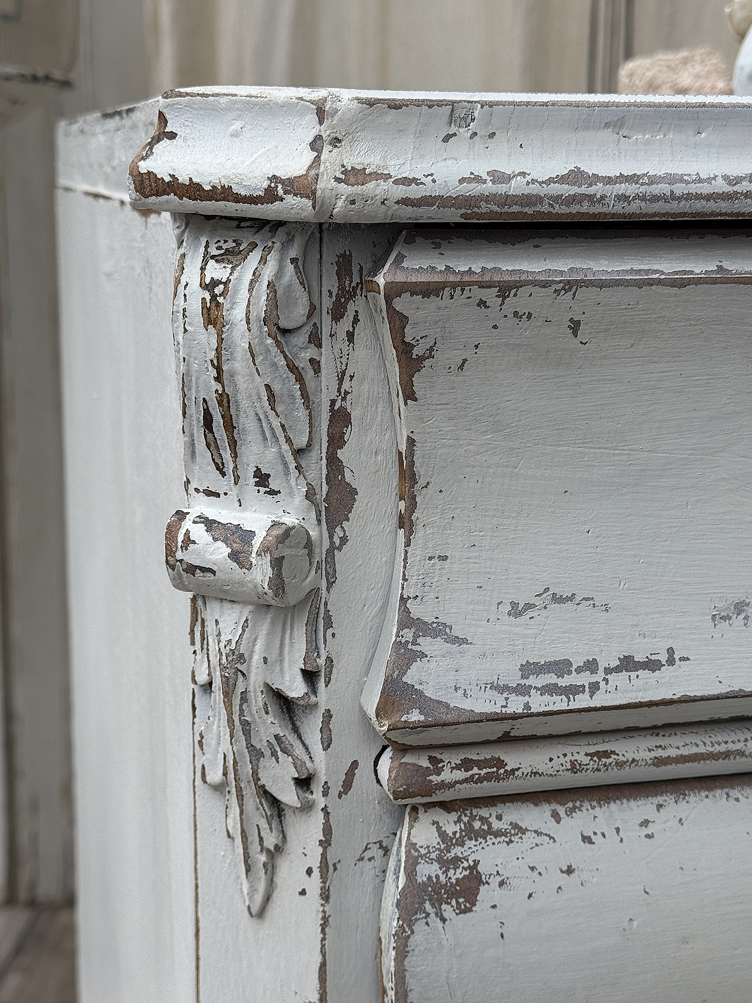 Detailansicht eines antiken Sideboards mit abblätternder Farbe und floralem Dekor