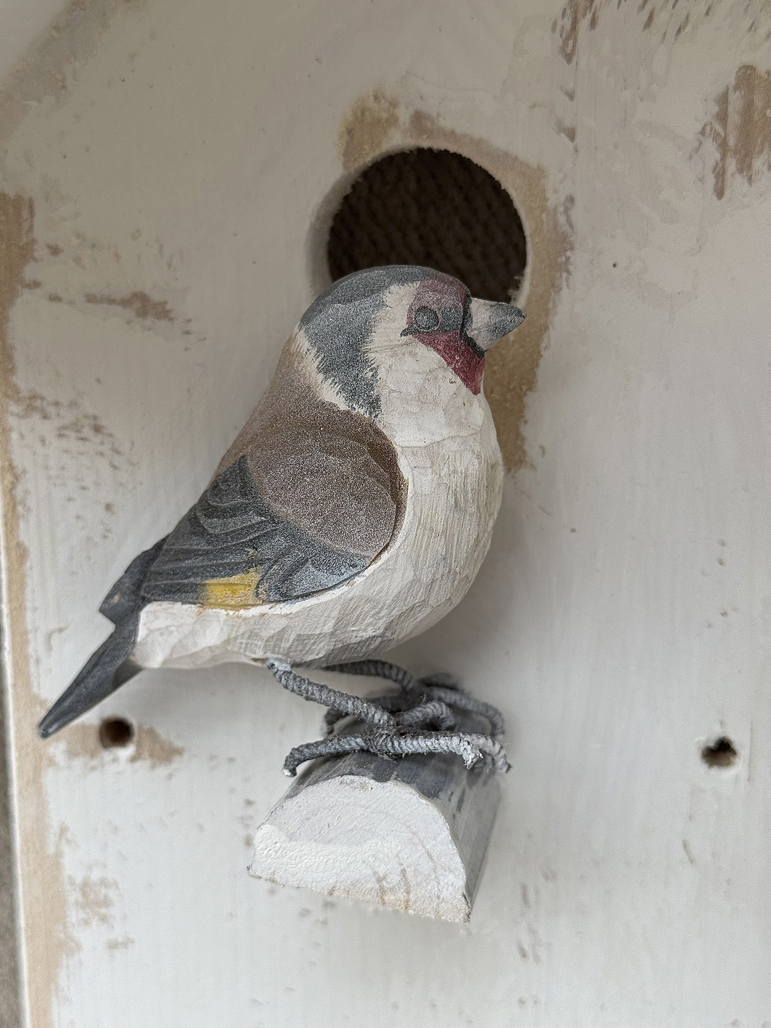 Dekorativer hölzerner Vogel vor einem Nistkasten, kunstvoll geschnitzt