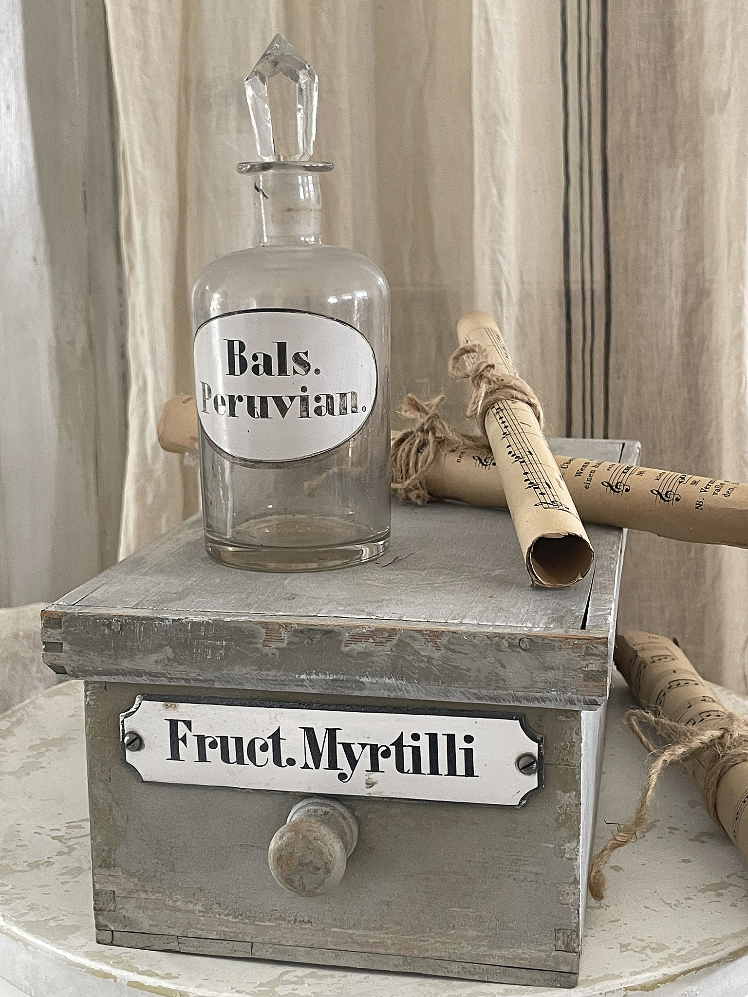 Vintage Glasflasche mit Aufschrift 'Bals. Peruvian.' auf einer Holzschublade mit der Beschriftung 'Fruct. Myrtilli'.